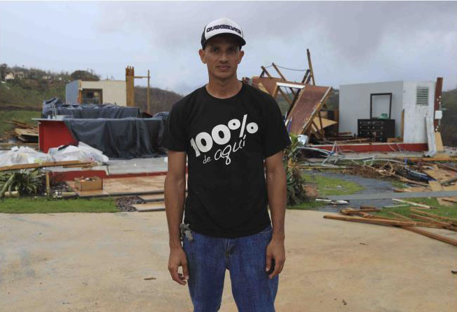 Morovis, Puerto Rico. Un agricultor de cuarenta y un años de edad, casado y con un hijito de nueve años de edad, se para frente a lo poco que queda de la casa de la familia después del paso del huracán María.